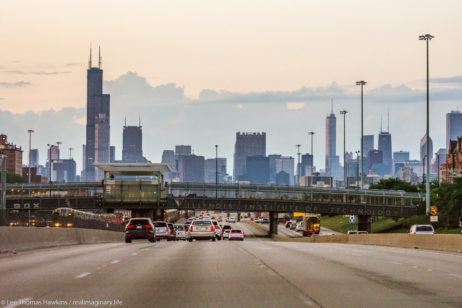 Cars drive north into the Downtown Chicago skyline on the Dan Ryan Expressway at sunset