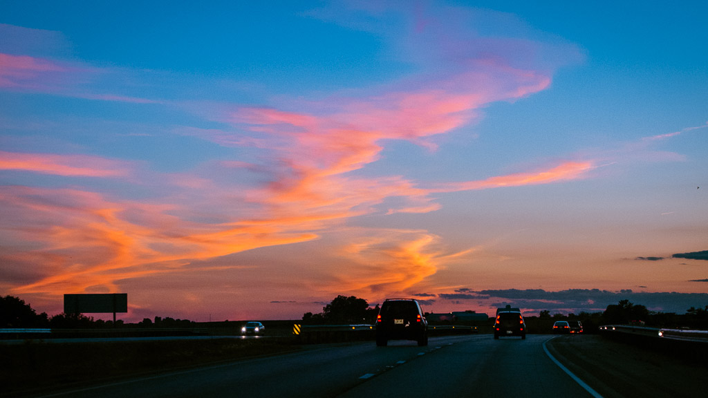 Orange and pink clouds veil parts of a blue sky after sunset as cars drive on I-80 in Spring Valley, Illinois.