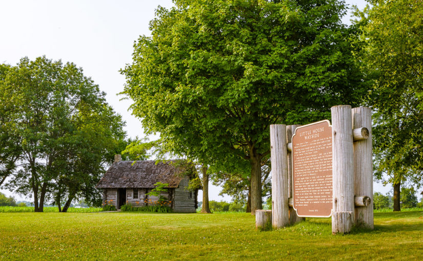 A replica log cabin and historical marker stand on the site of Laura Ingalls Wilder's birthplace and the location of her book, Little House in the Big Woods.
