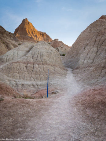 Looking up the Saddle Pass Trail in Badlands National Park. Blue markers help to identify the trail amid the indistinct terrain.